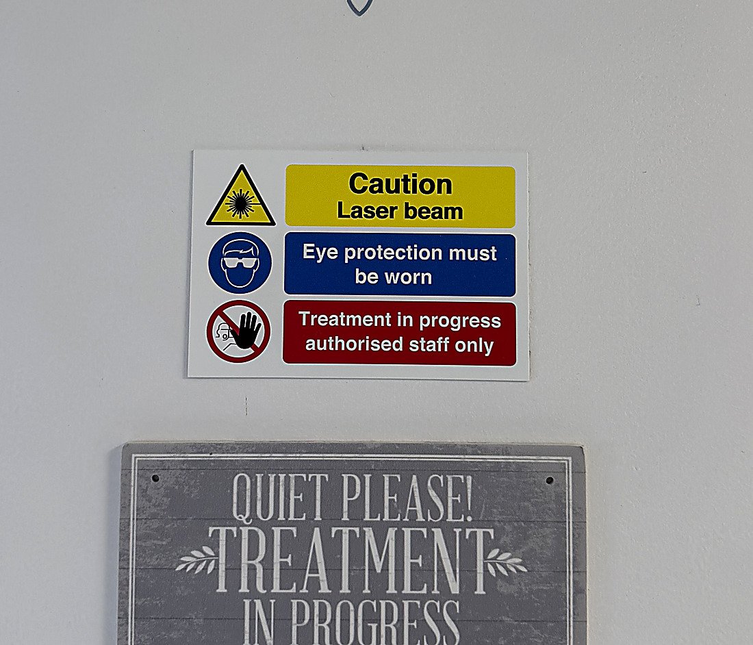 The laser safety signs outside the Skintastic treatment room: caution laser beam, eye protection must be worn, treatment in progress authorised staff only
