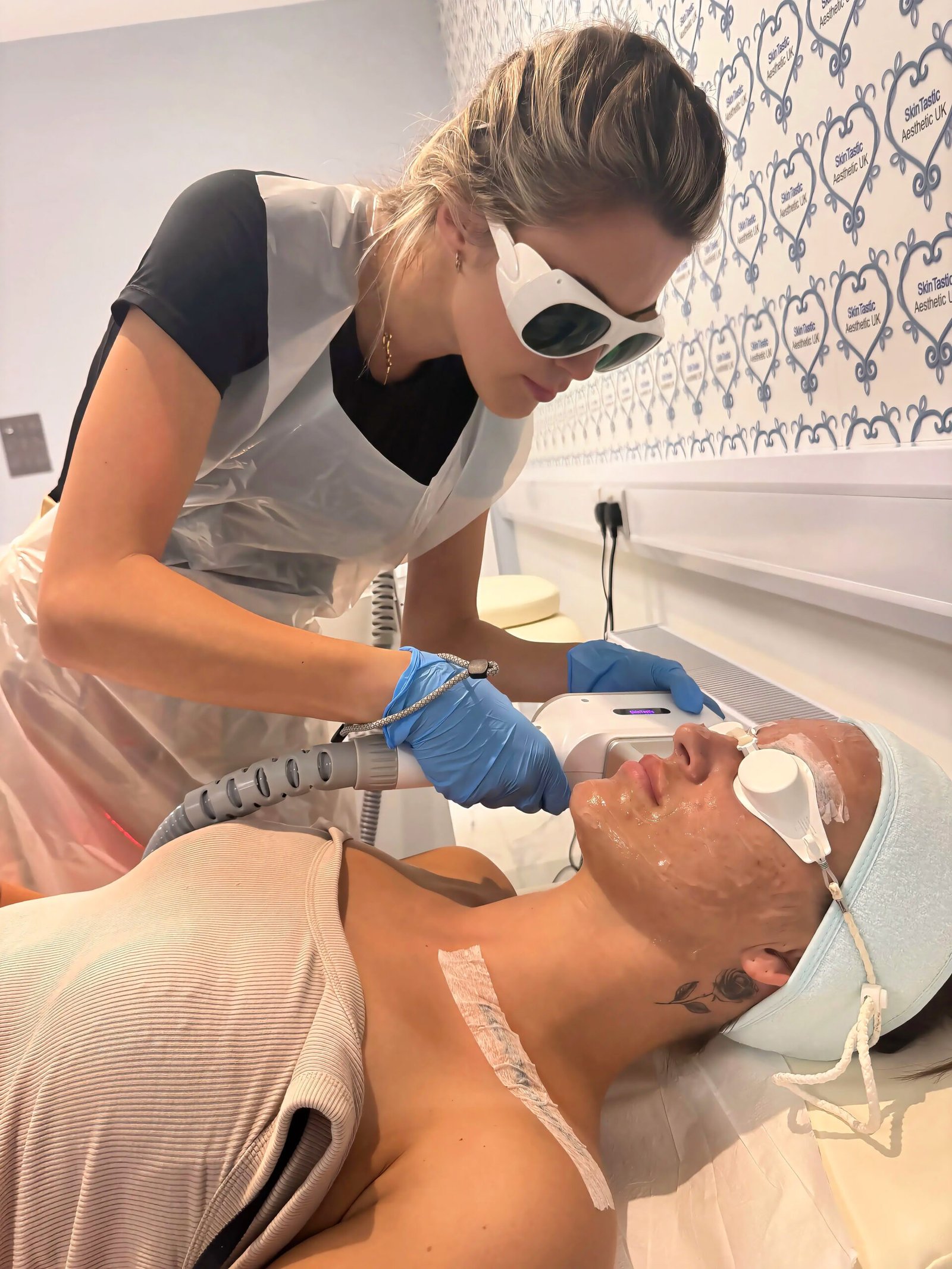 A Skintastic practitioner wearing laser safety glasses carries out an IPL skin rejuvenation treatment on a client wearing protective eye shields, at the Southampton clinic