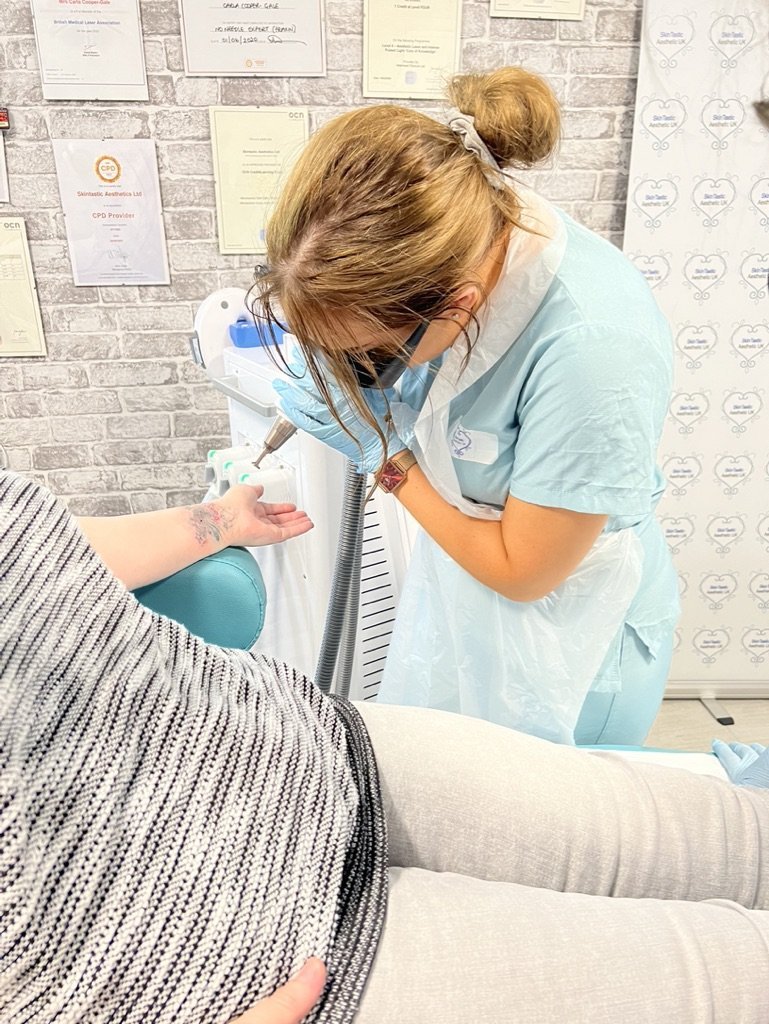 Carla Cooper-Gale performing laser tattoo removal treatment on a client’s forearm at Skintastic Aesthetics